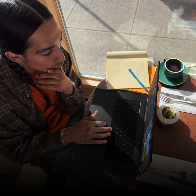 Una persona en una cafetería trabaja con una MacBook Pro que no está conectada a la corriente
